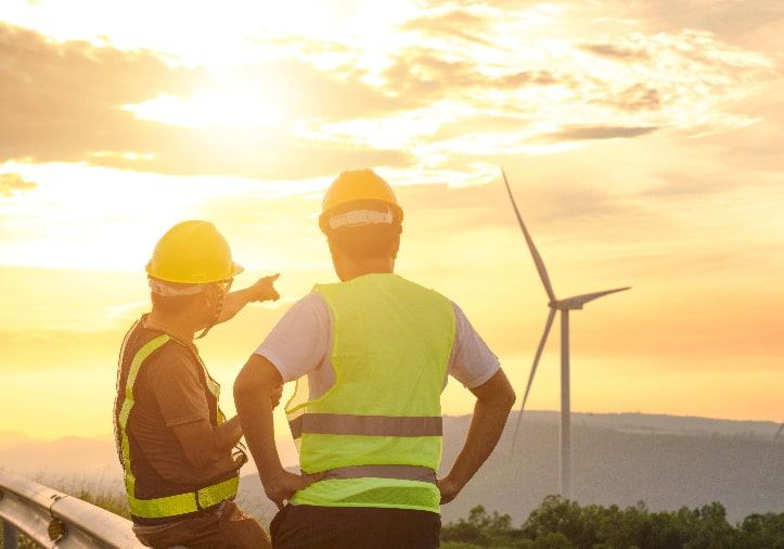 STP site managers in front of a wind turbine at sunset